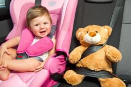 Kind in Kindersitz mit Teddy